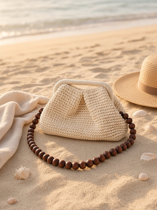 Yazli Raffia Clutch in Creme with wooden bead strap on beach sand